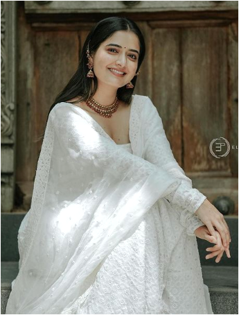 Ashika Ranganath seated on steps in white attire